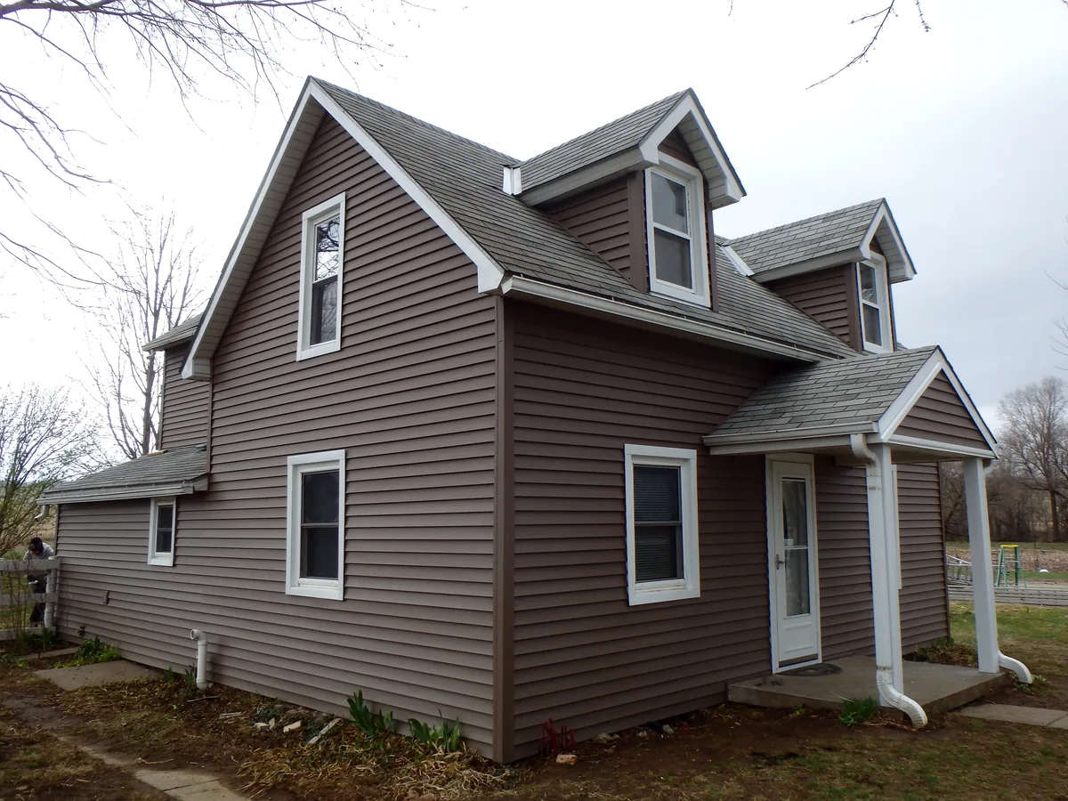 Story-and-a-half home with brown siding and white trim