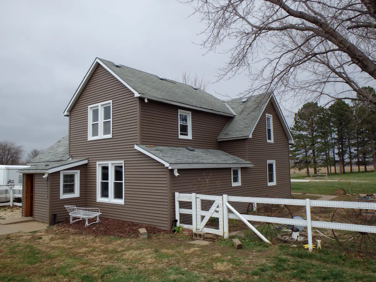 Brown-sided farmhouse behind a white fence