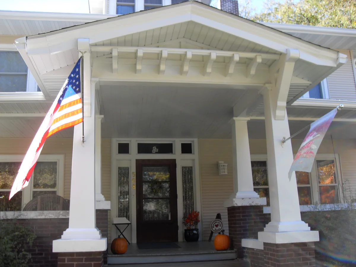 Covered front porch with white columns and a flag
